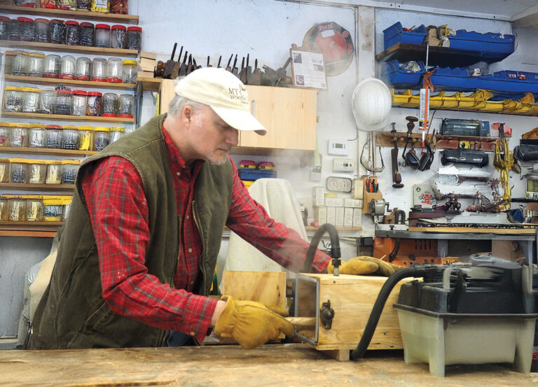 Man woodworking in a workshop with tools.