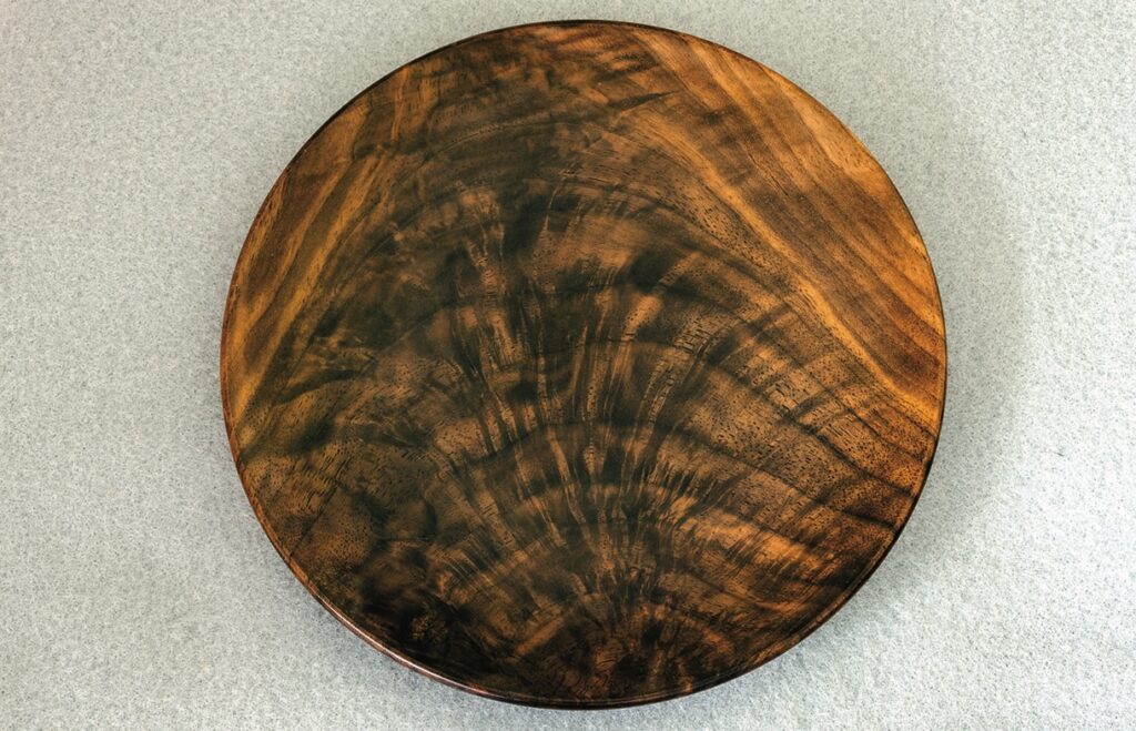 Round wooden platter with unique grain pattern.