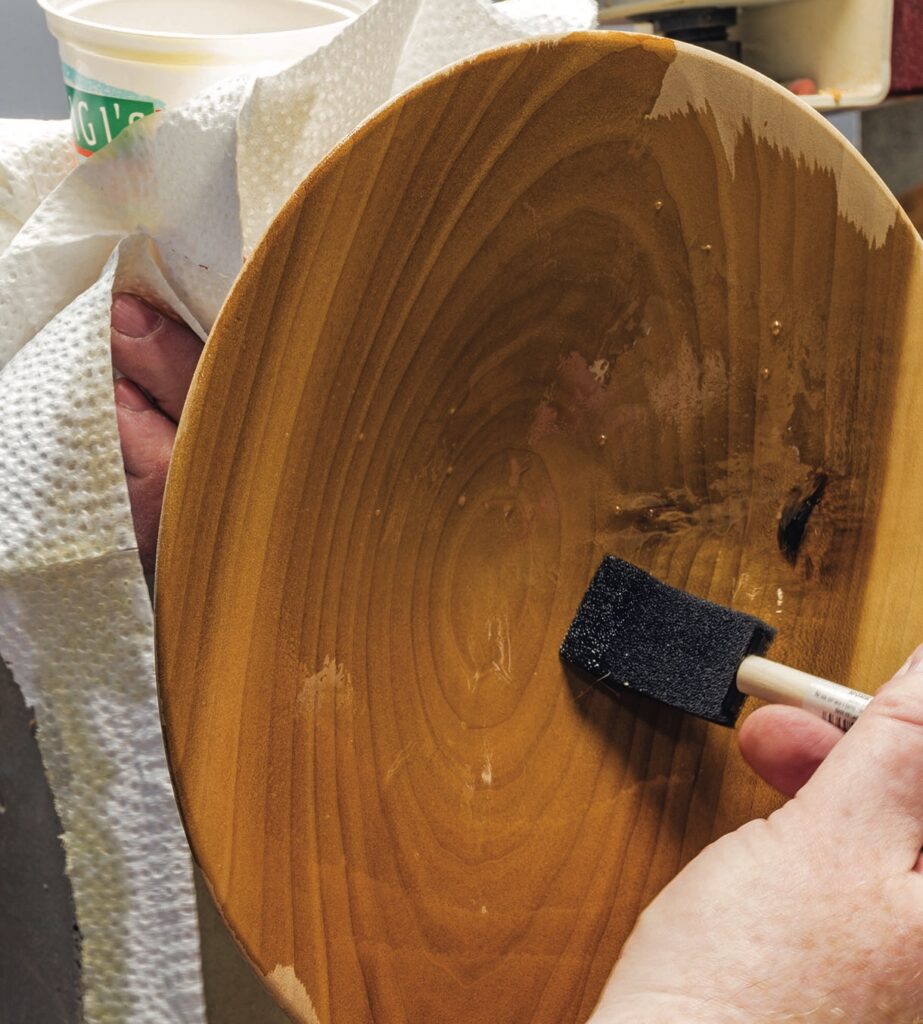 Applying varnish to wooden surface with brush.