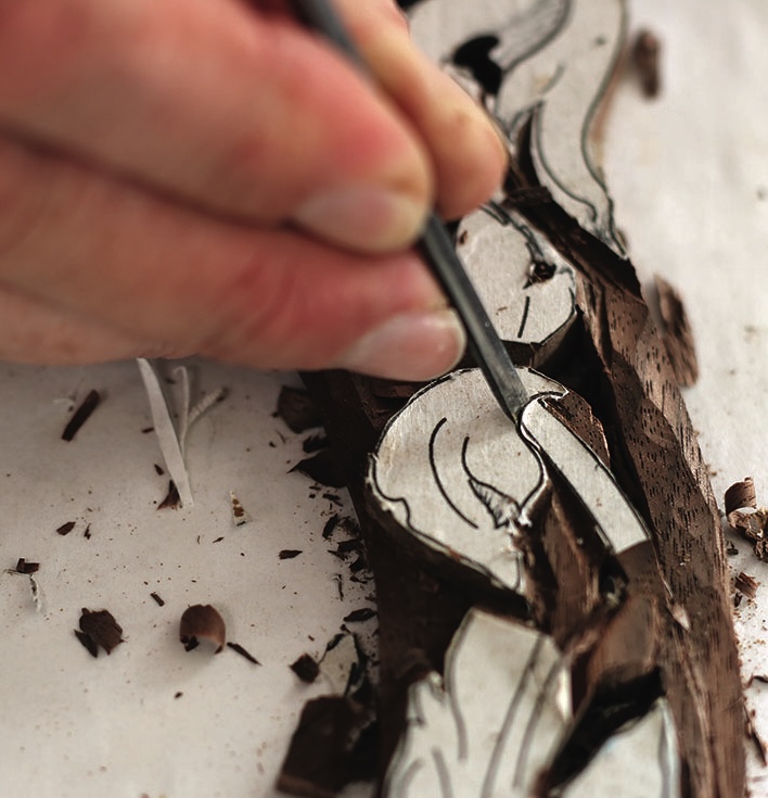 Hand carving intricate woodblock design in progress.