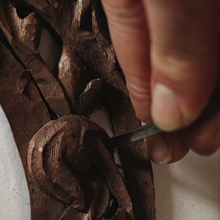 Hand carving details into wooden sculpture