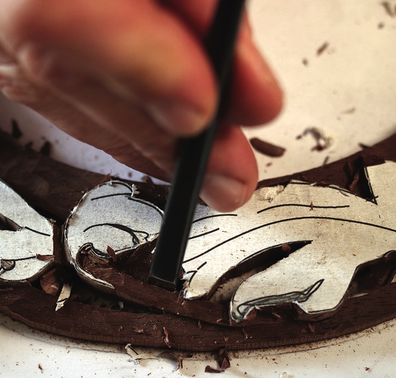 Hand carving wood with a chisel.