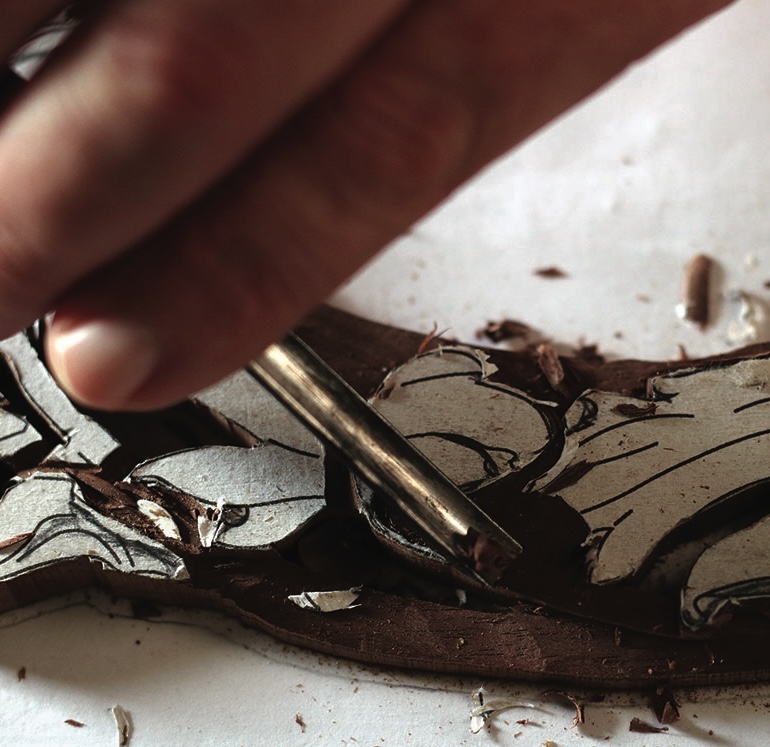 Hand chiselling intricate wood carving design