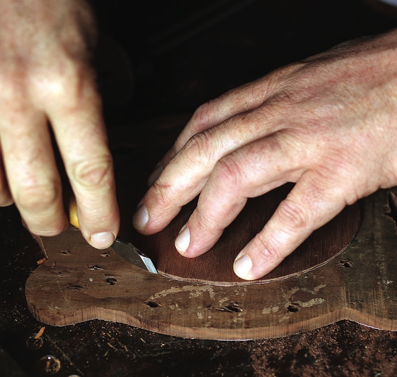 Craftsman carving wood with hand knife.