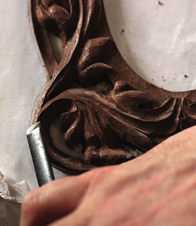 Hand carving intricate wooden design with chisel.