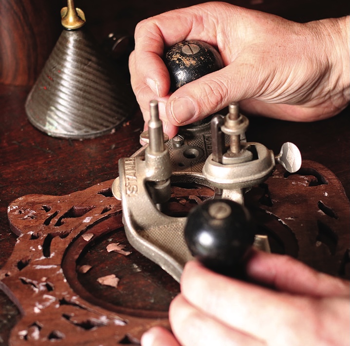 Hands operating a vintage mechanical device on wood.