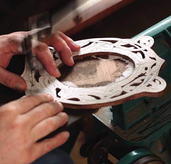 Woodworker carving intricate floral design on wooden piece.