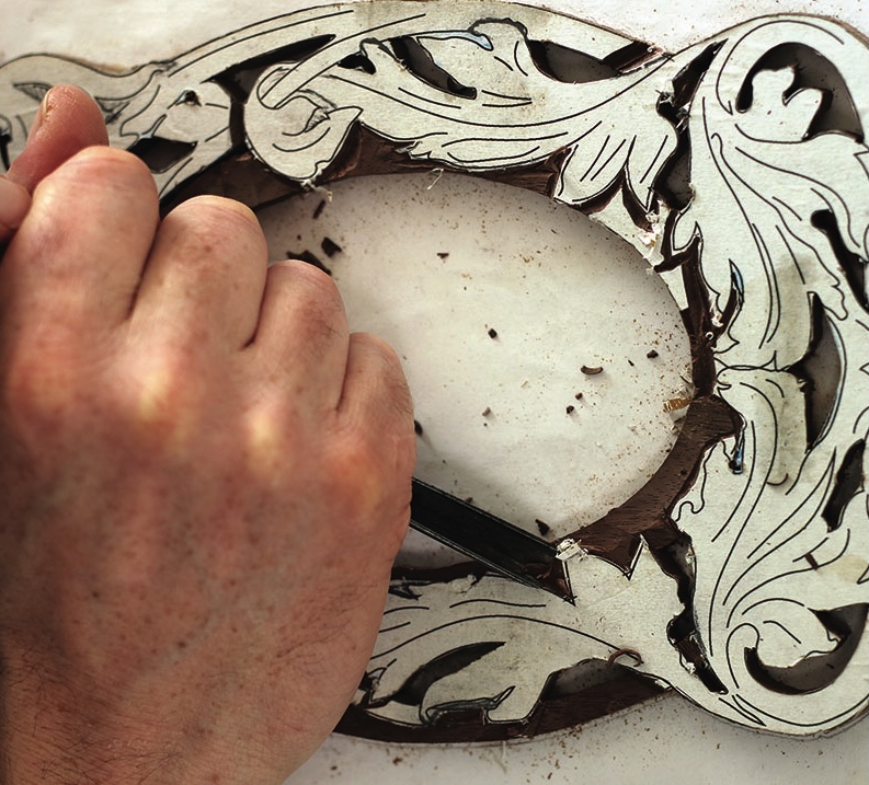 Hand carving intricate wood design.