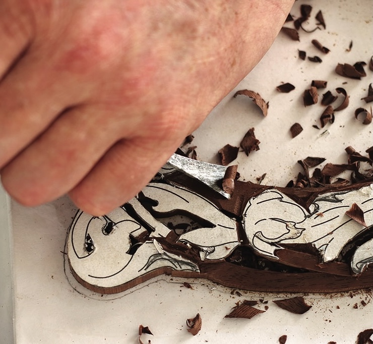 Hand carving detailed wooden design with chisel.