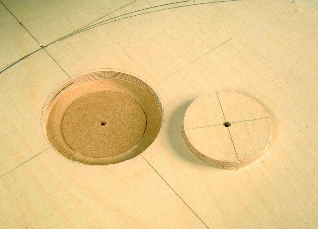 Wooden round cutouts on workbench with pencil marks.