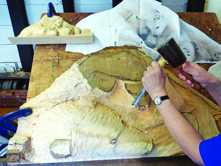 Person carving polar bear from wood block