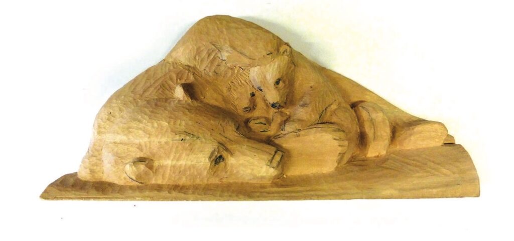 Wooden carving of bears resting together.