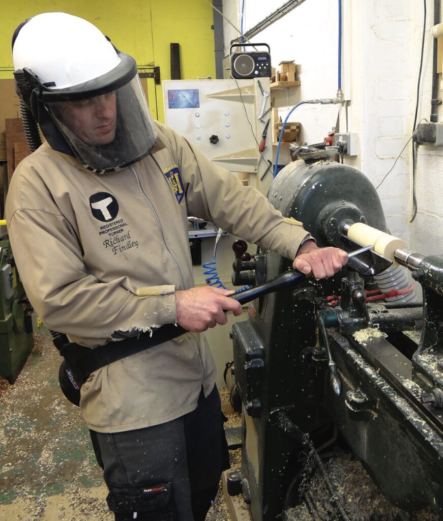 Woodturner shaping wood on lathe in workshop.