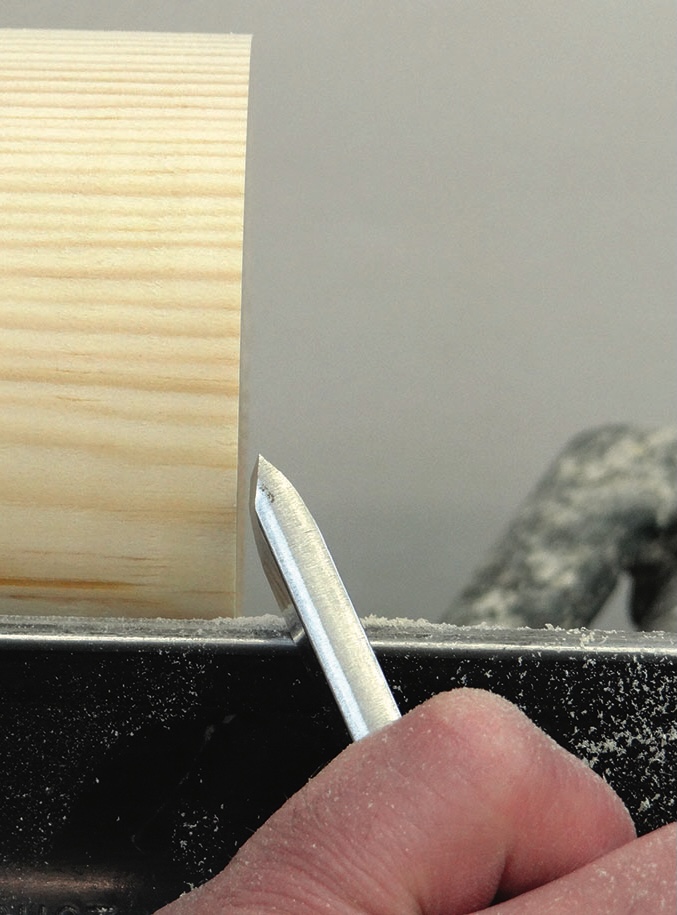 Hand chiselling wood on lathe, close-up view.