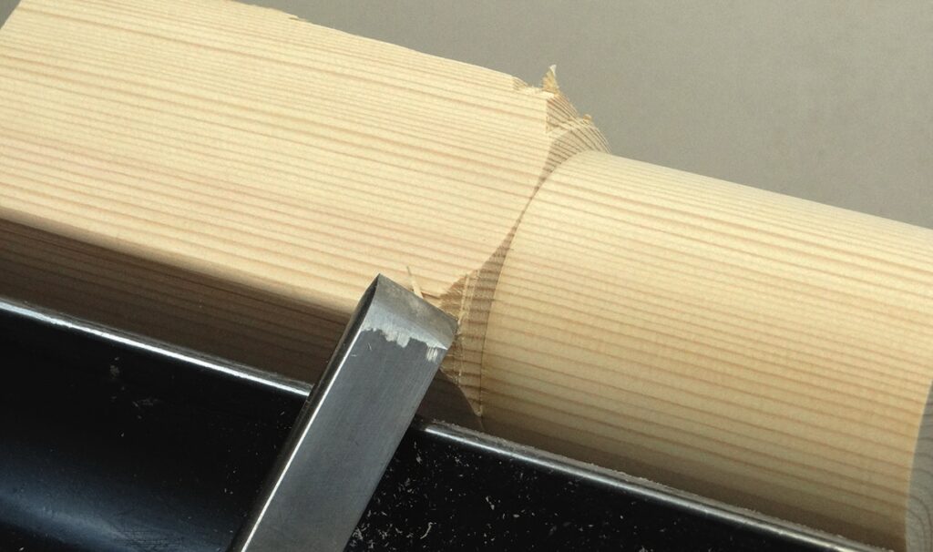 Woodturning tool carving round wooden piece.