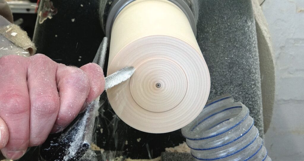 Person shaping wood on a lathe.