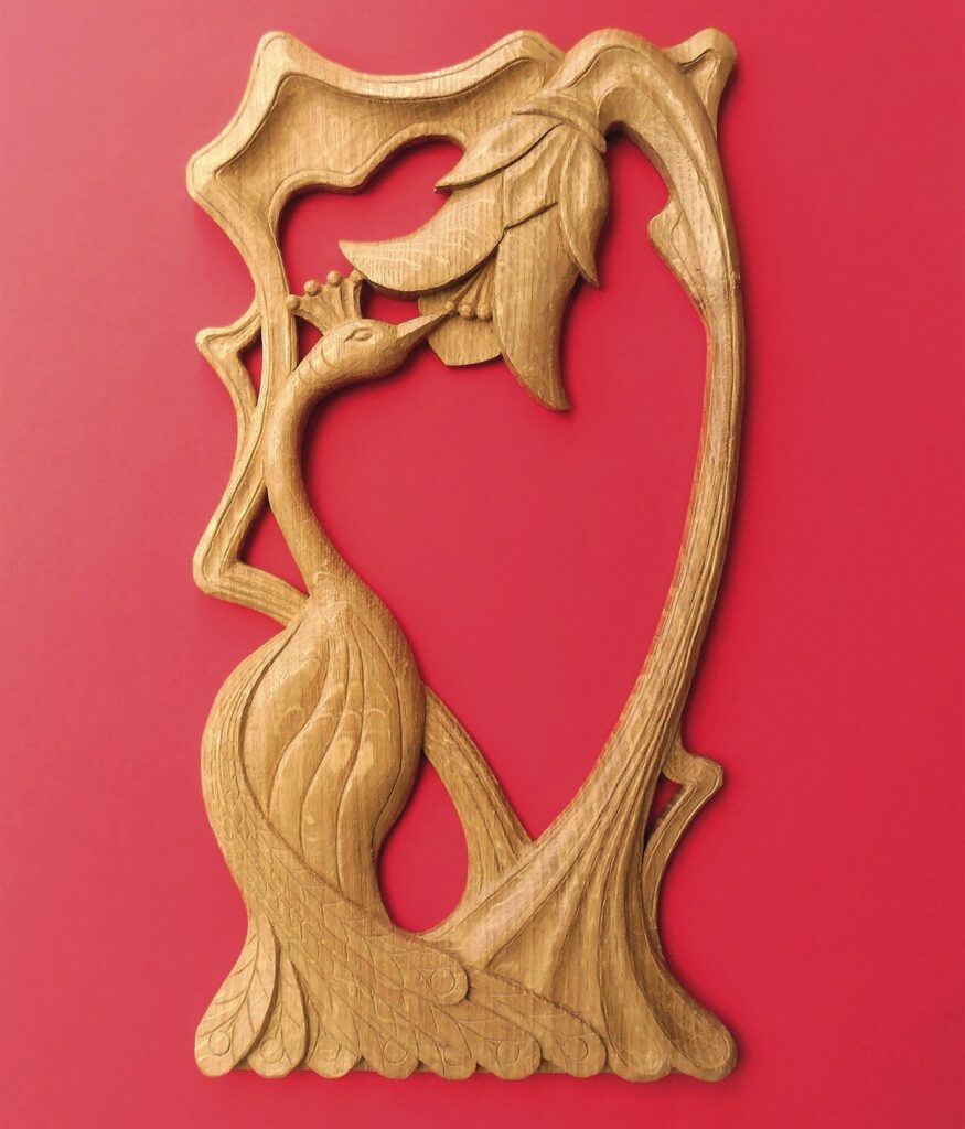 Wooden carving of peacock and flower on red background.