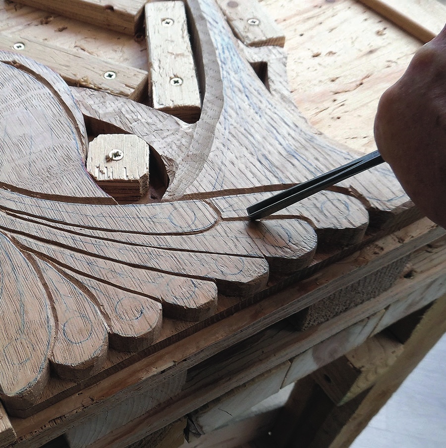 Craftsman chiselling intricate wood carving detail