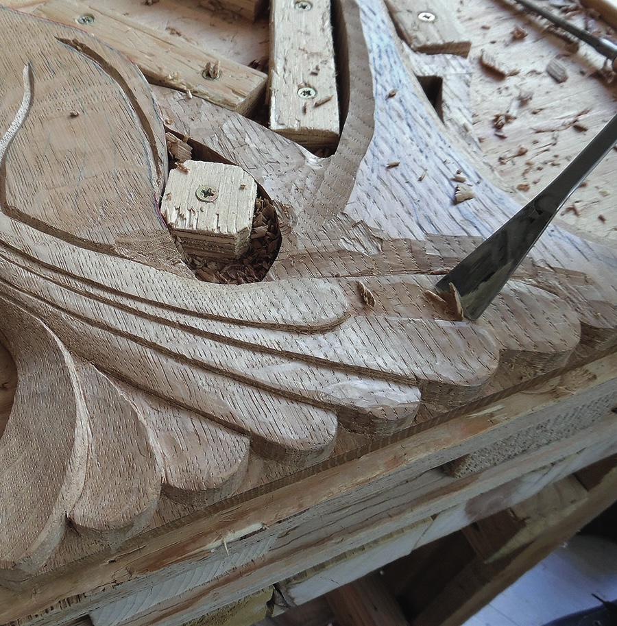 Wood carving in progress with chisel tool.