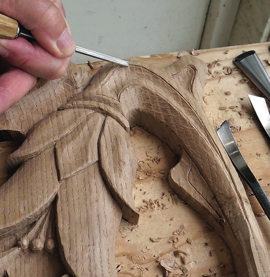 Hand carving intricate wood design with chisel