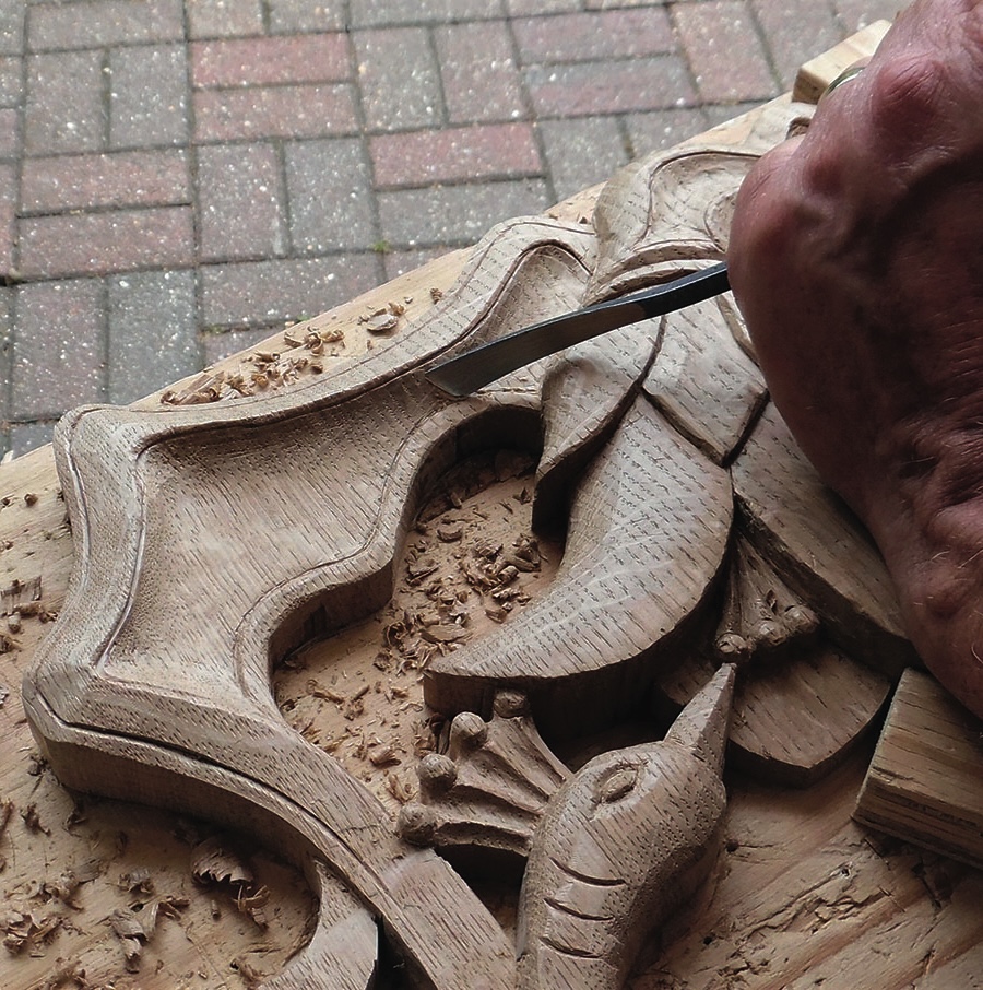 Hand carving intricate wooden design with chisel.