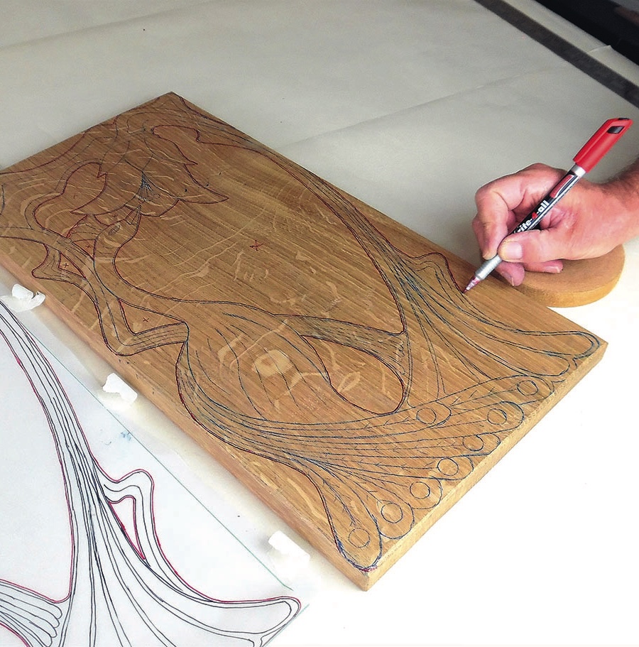 Person drawing on wooden board with pen