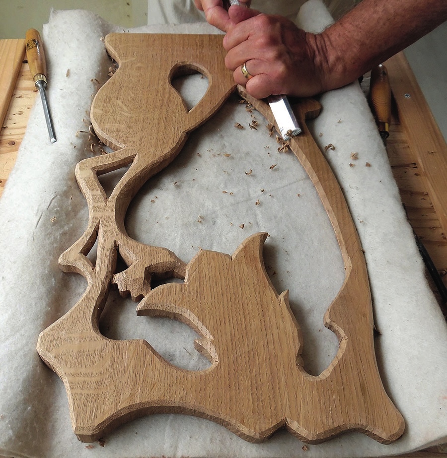 Person hand-carving wooden relief sculpture with chisels.