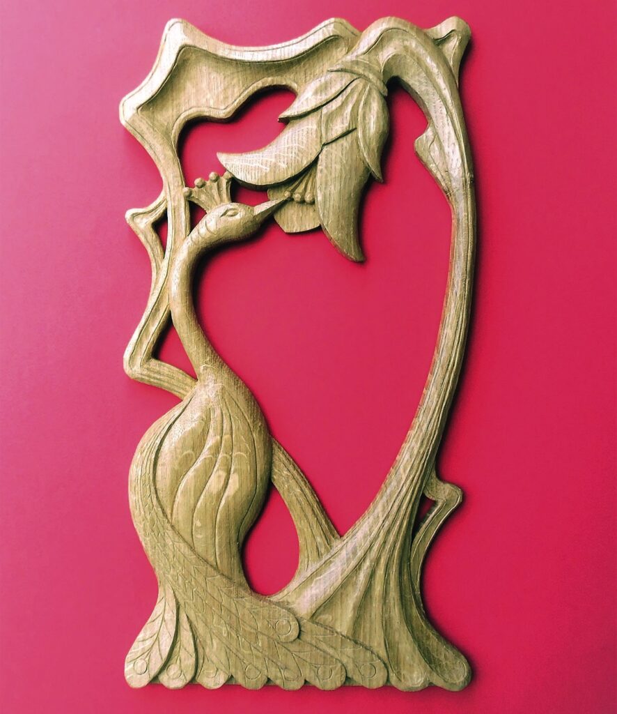 Intricate wooden bird carving on red background.