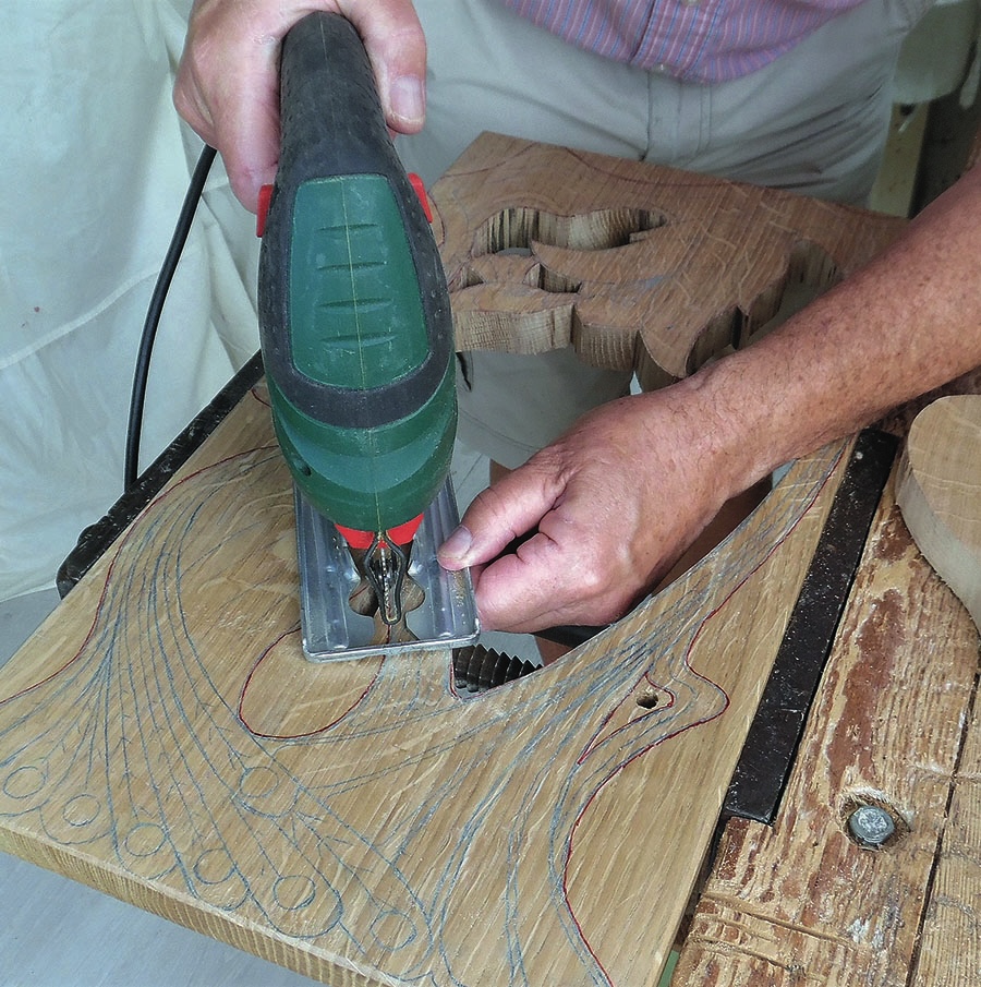 Person using jigsaw to cut wood design.