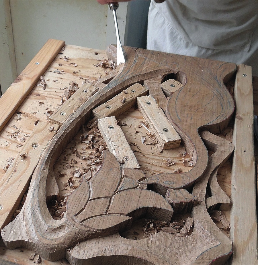 Person carving decorative wood design.