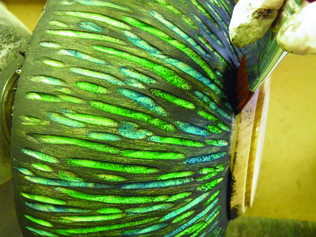 Hand painting vibrant green and blue on pottery.