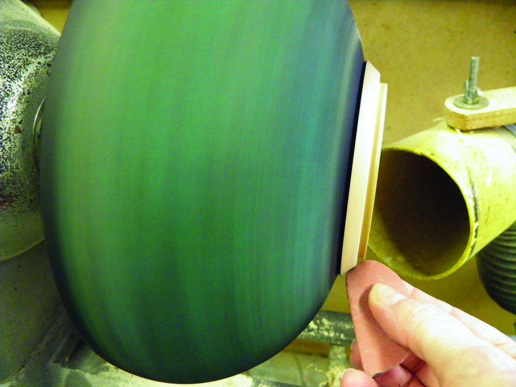 Hand sanding spinning wooden bowl on lathe