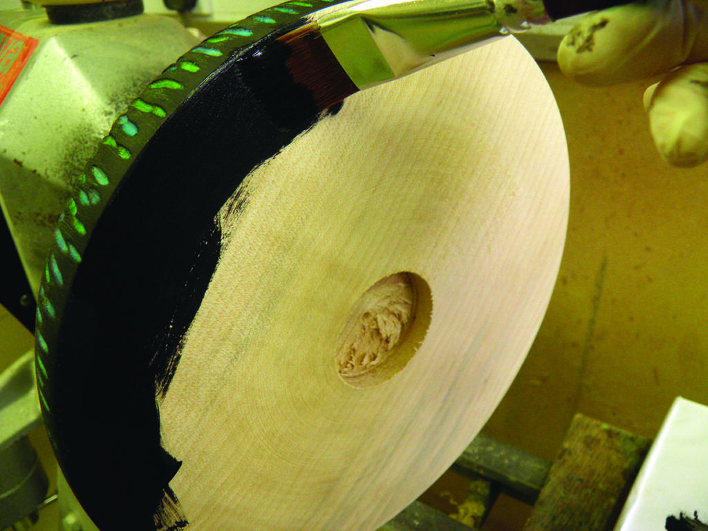 Painting wooden wheel with black paint.