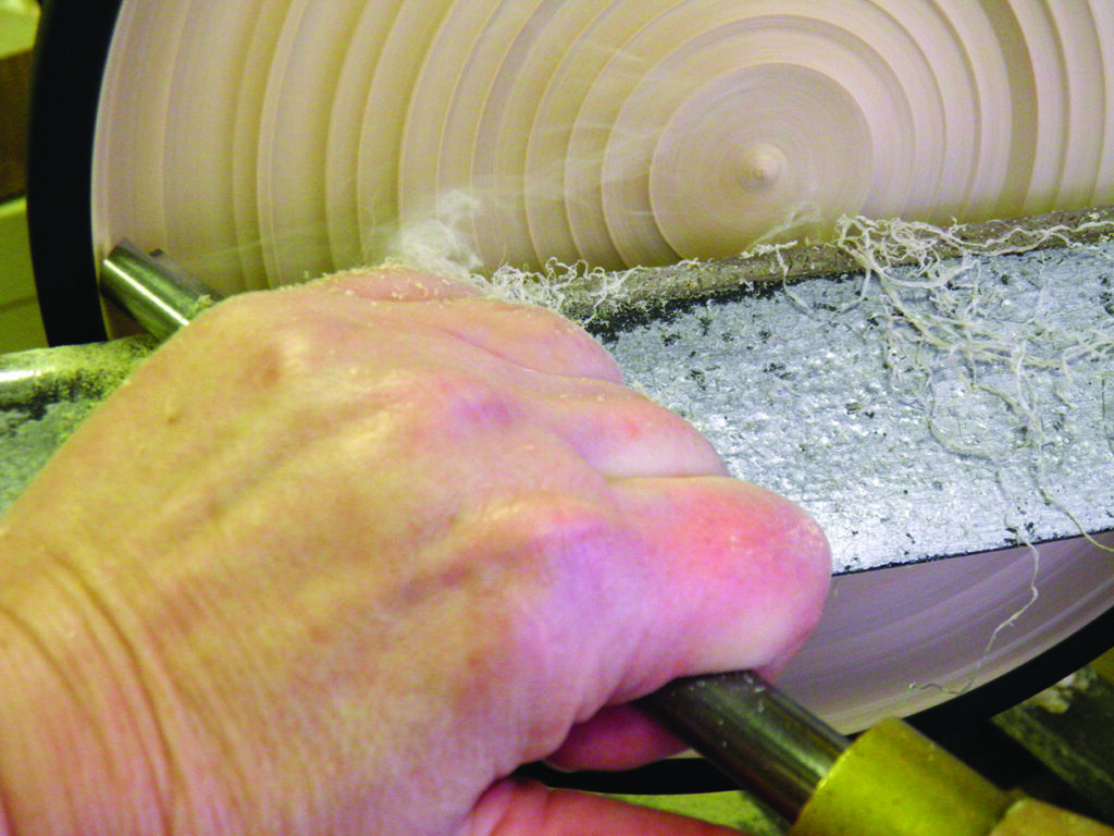Close-up of woodturning on lathe with tool.