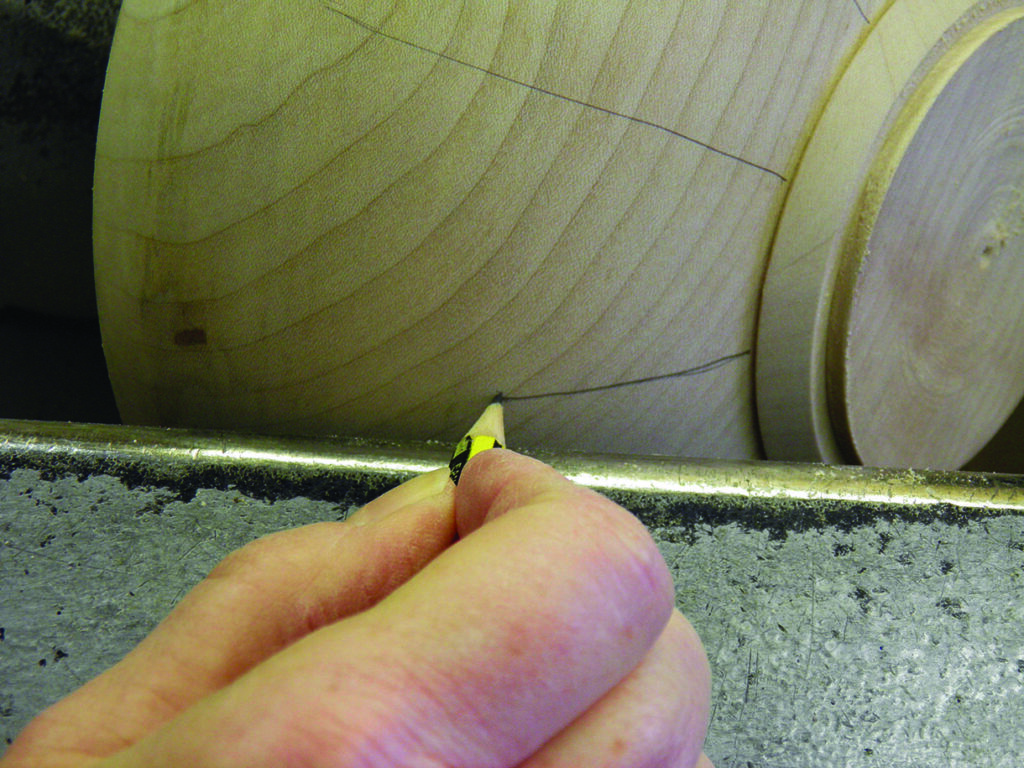 Woodturning: drawing guideline on wooden lathe piece.