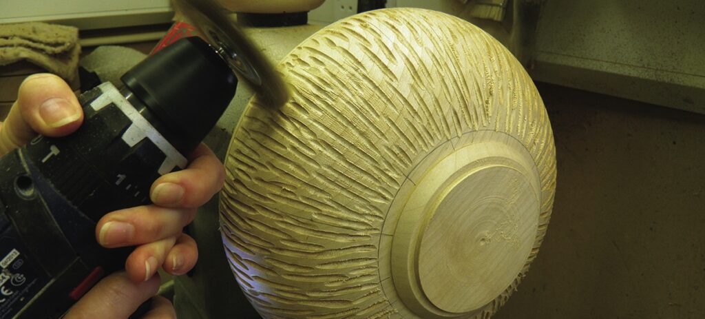 Person carving intricate design on wooden bowl.