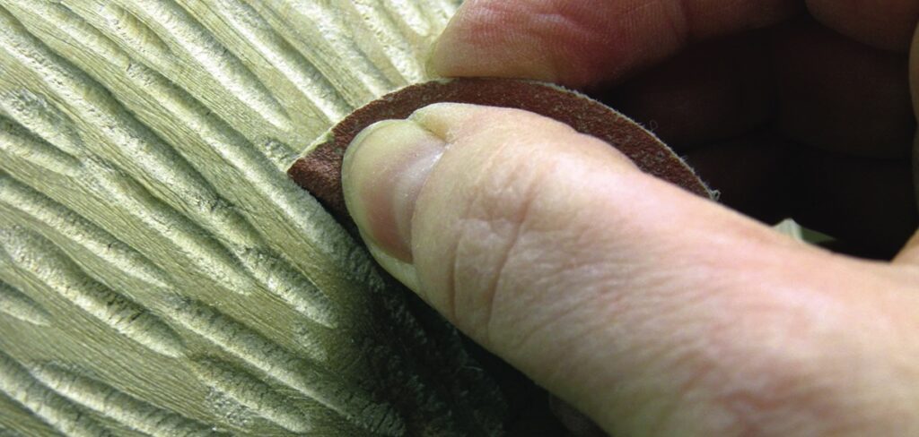 Hand sanding wood surface with sandpaper.