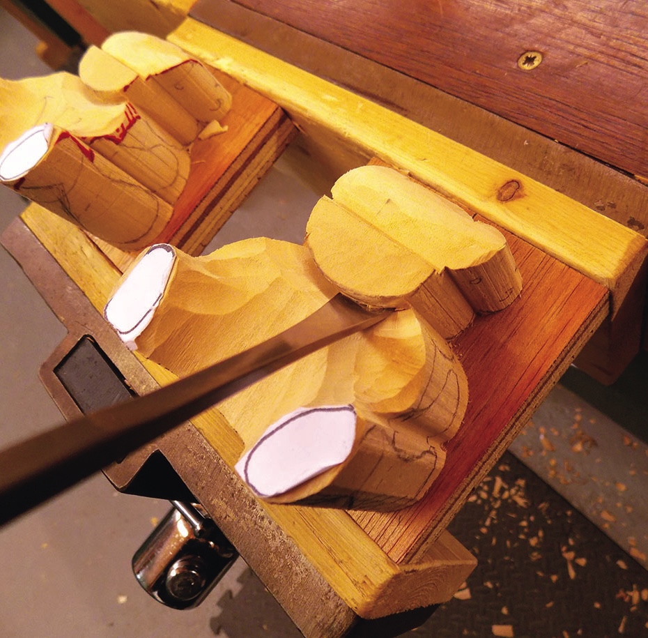 Carving wooden figures with a sharp chisel tool.