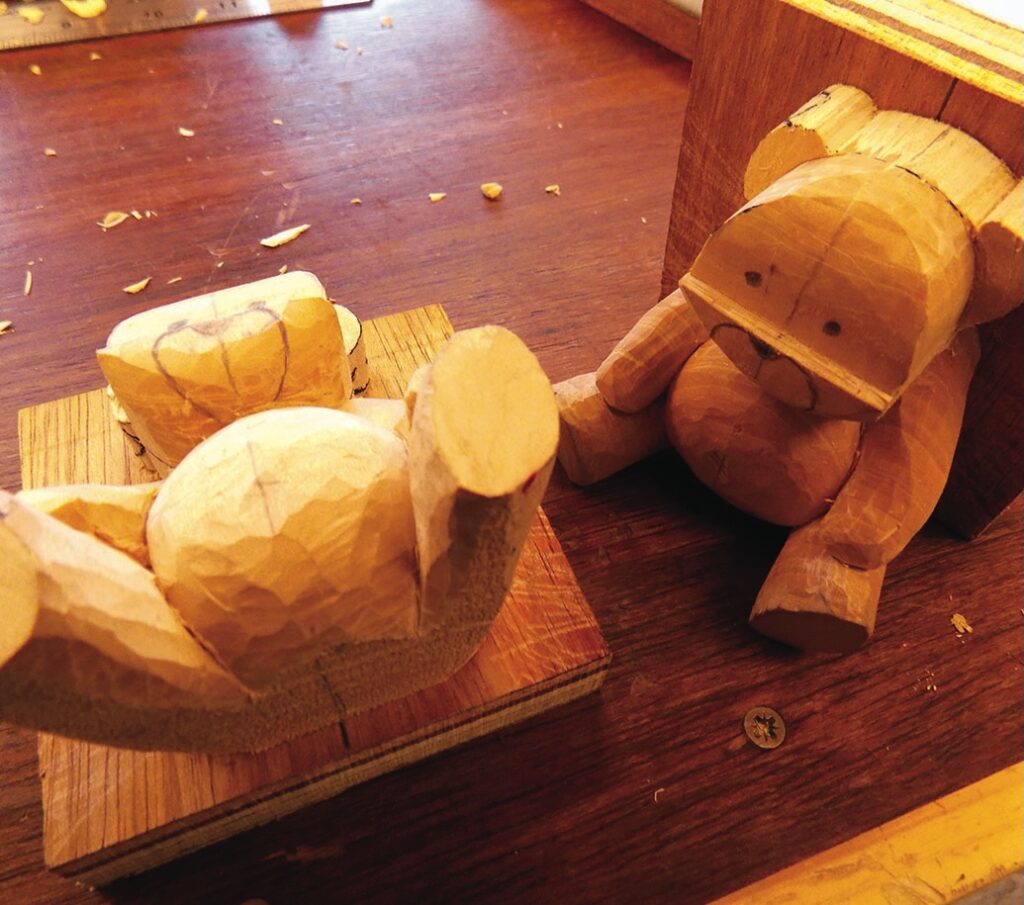 Wooden teddy bear carvings on a workbench
