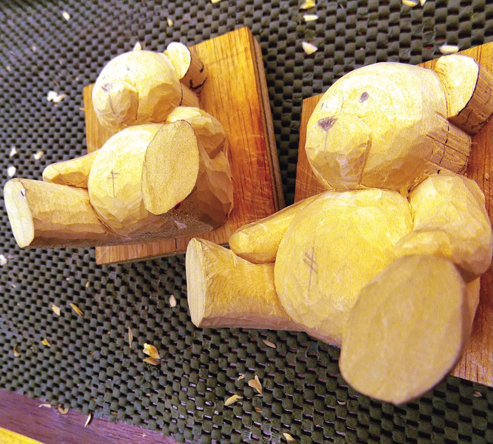 Wooden carved teddy bears on a table.