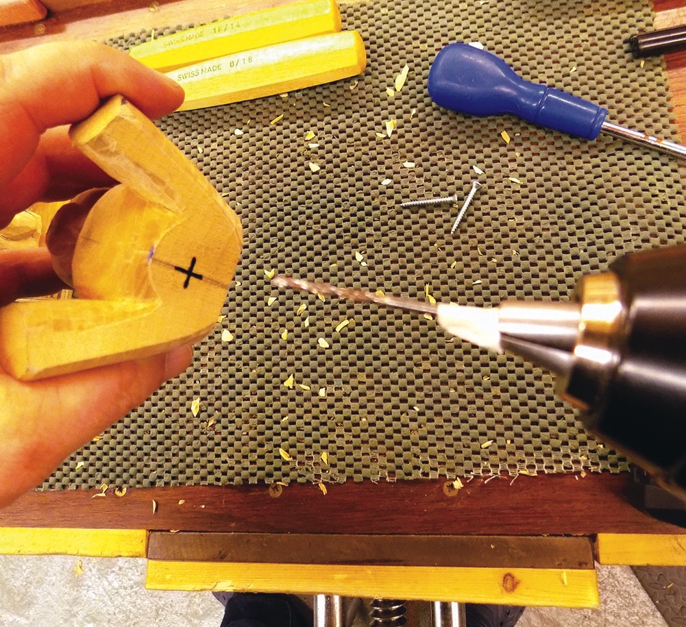 Person drilling into wooden piece in workshop.