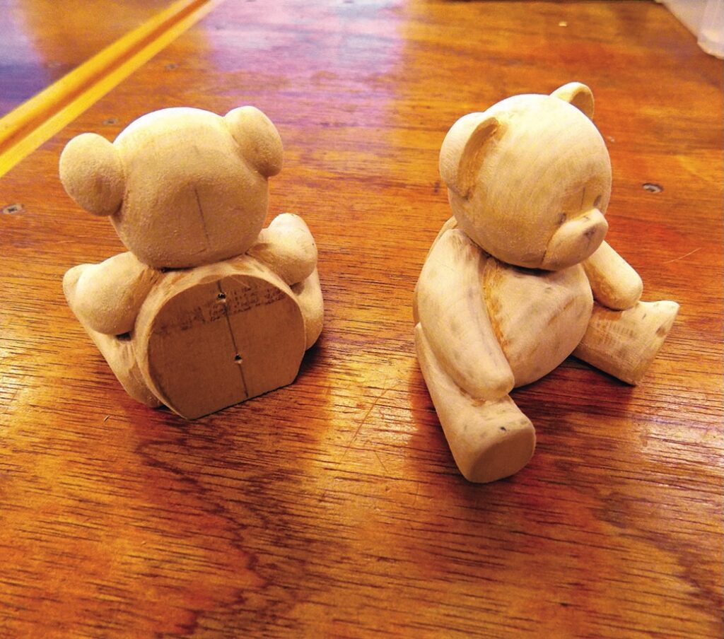 Wooden teddy bear carvings on a table.