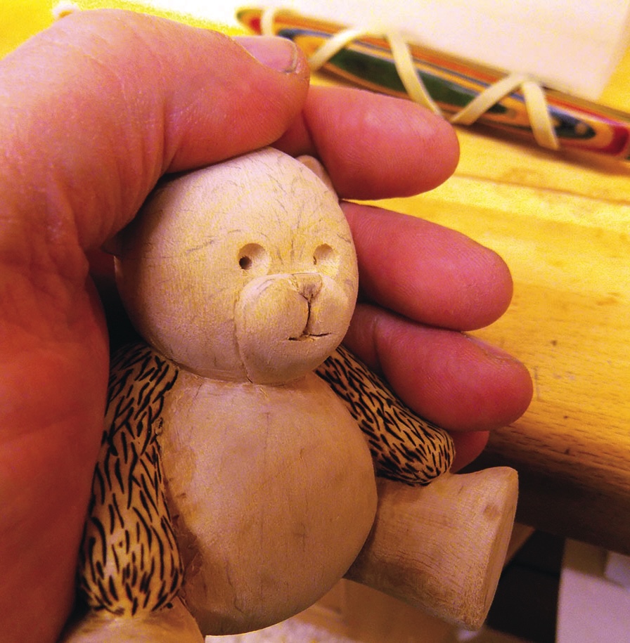 Hand holding carved wooden bear figurine