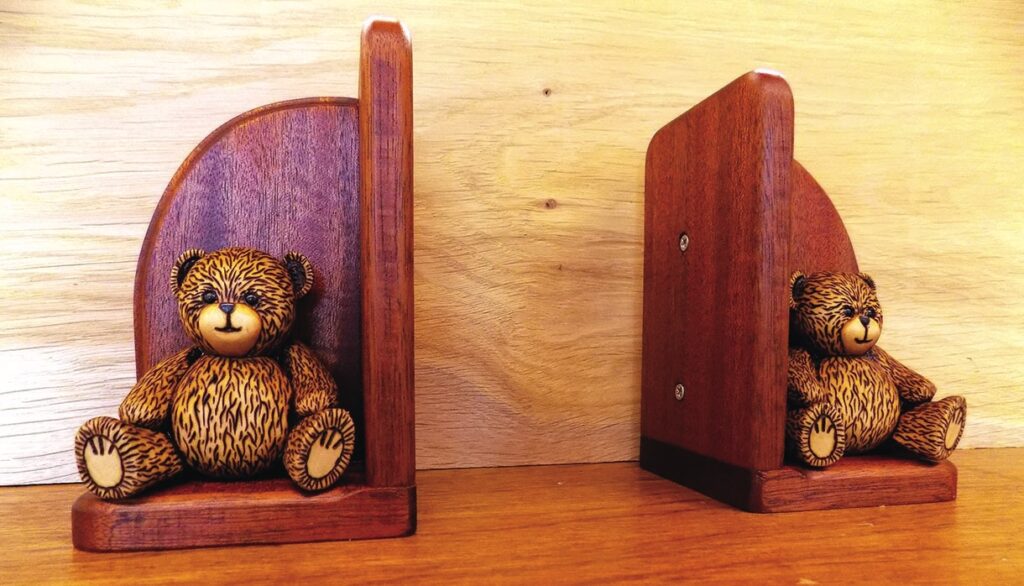Wooden teddy bear bookends on a shelf.