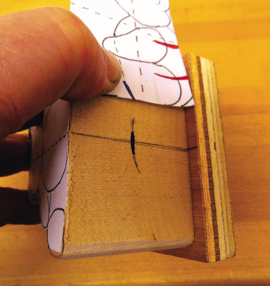 Hand holding wooden block with blueprint design.