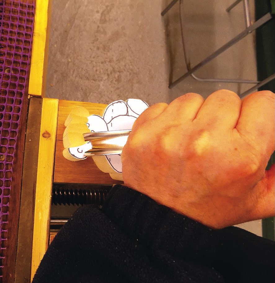 Hand-carving wooden piece with precision tool.