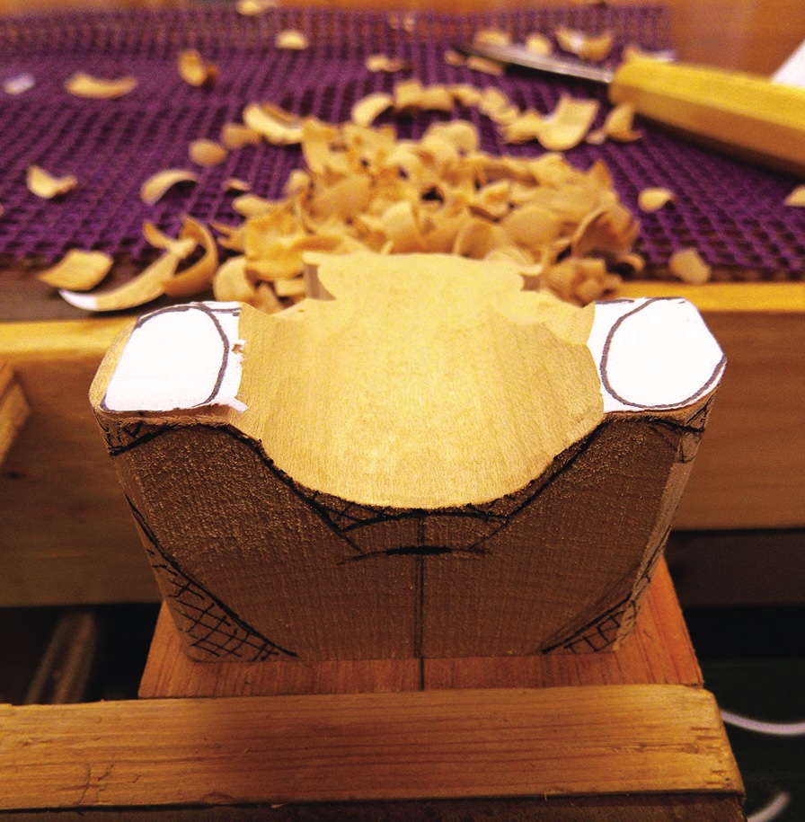 Wood carving block with shavings and gouge tool.