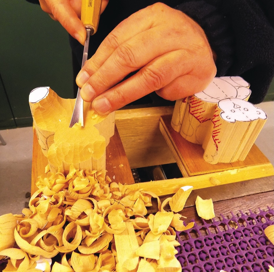 Hand carving wood with a chisel tool.