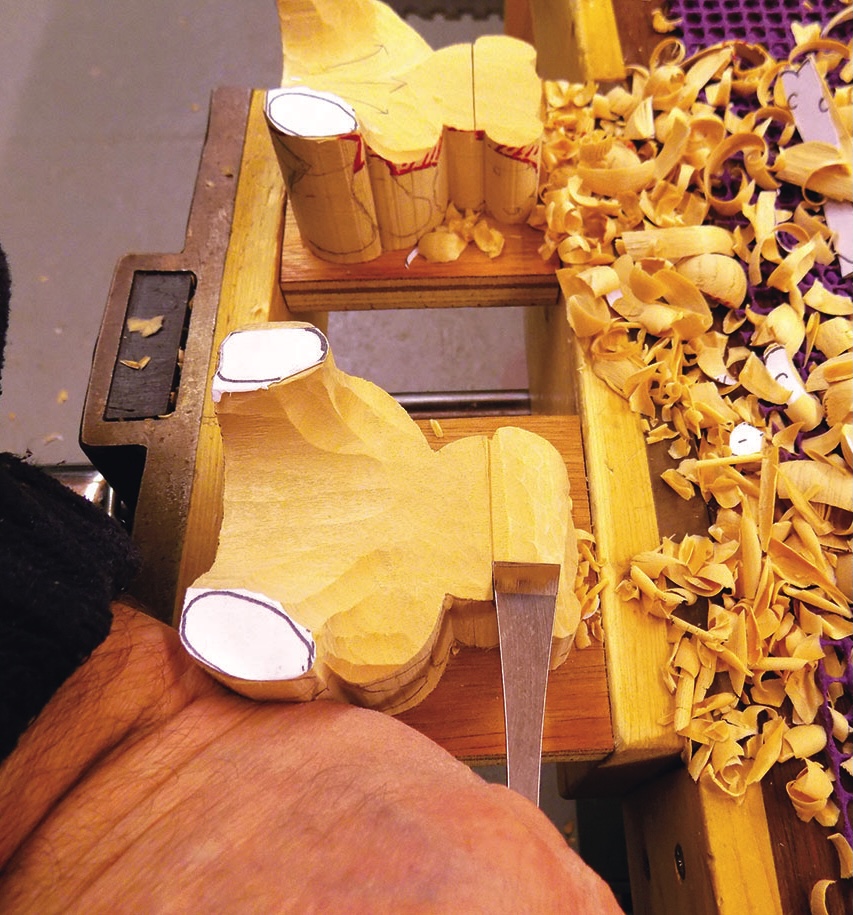 Woodcarving process with hand tool and shavings nearby.