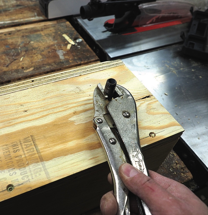 Using pliers to fix wood plank in workshop.